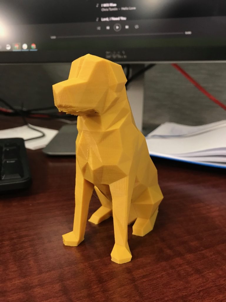 A yellow 3D printed dog on a desk